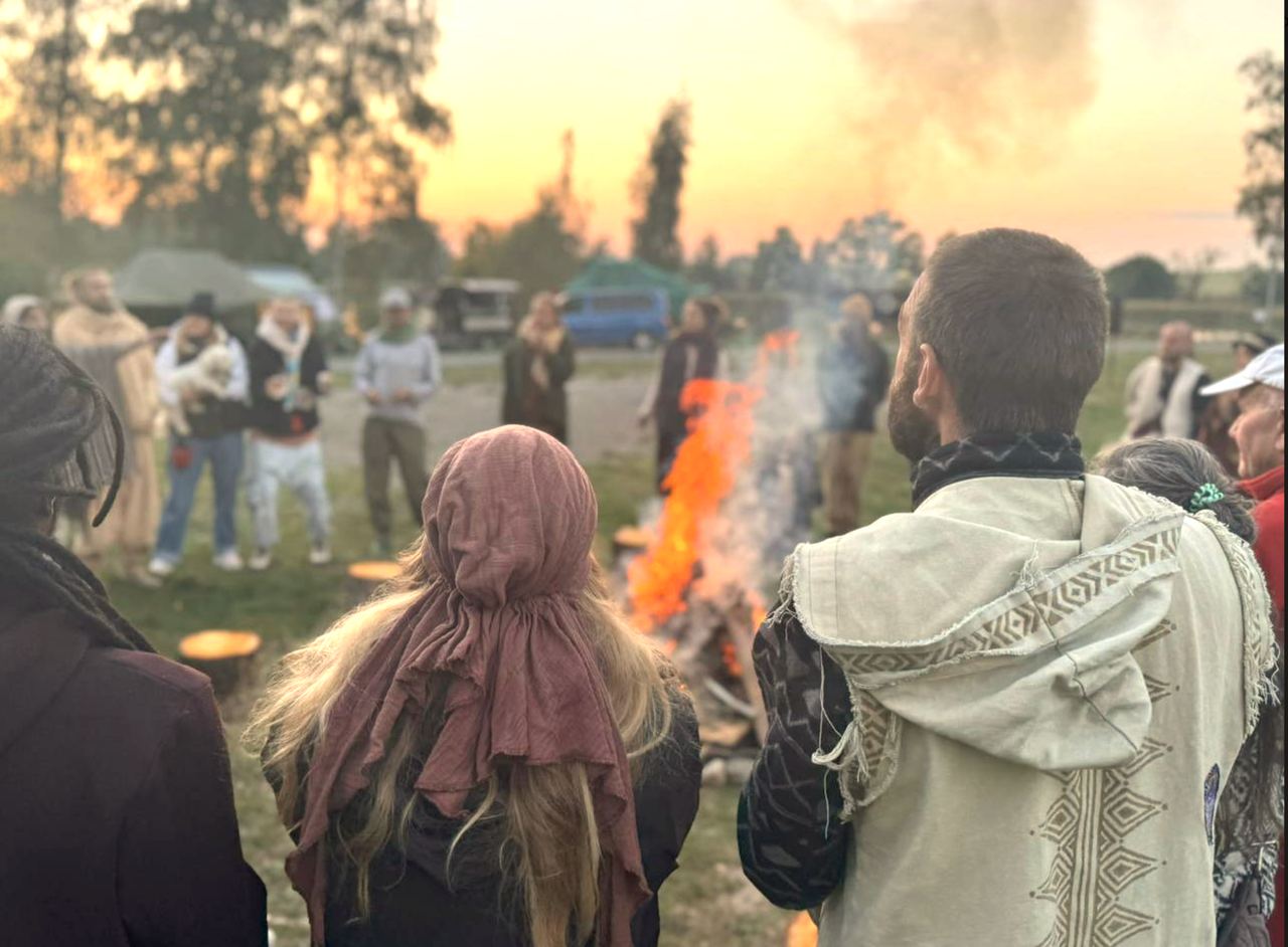 Menschen im Kreis am Lagerfeuer bei Sonnenuntergang