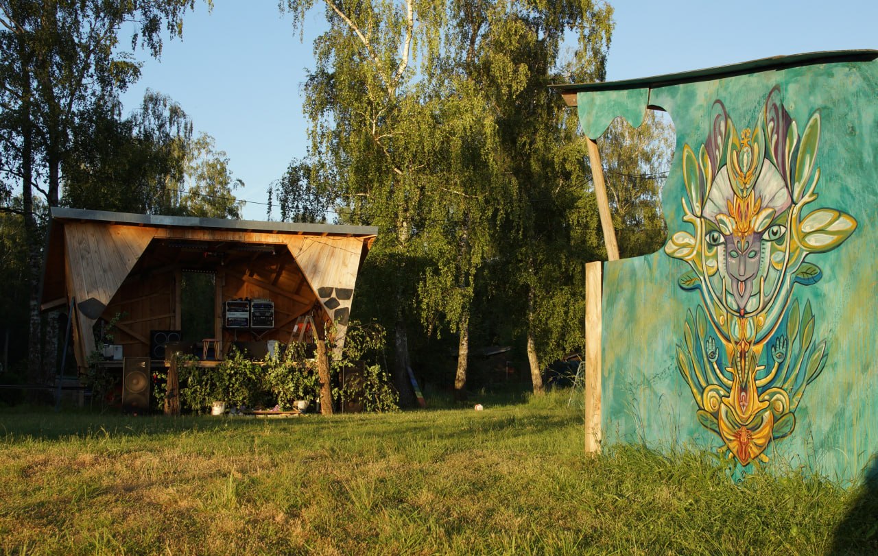 Open-Air-Bühne mit Soundsystem und bemalter Kunstwand auf der Wiese