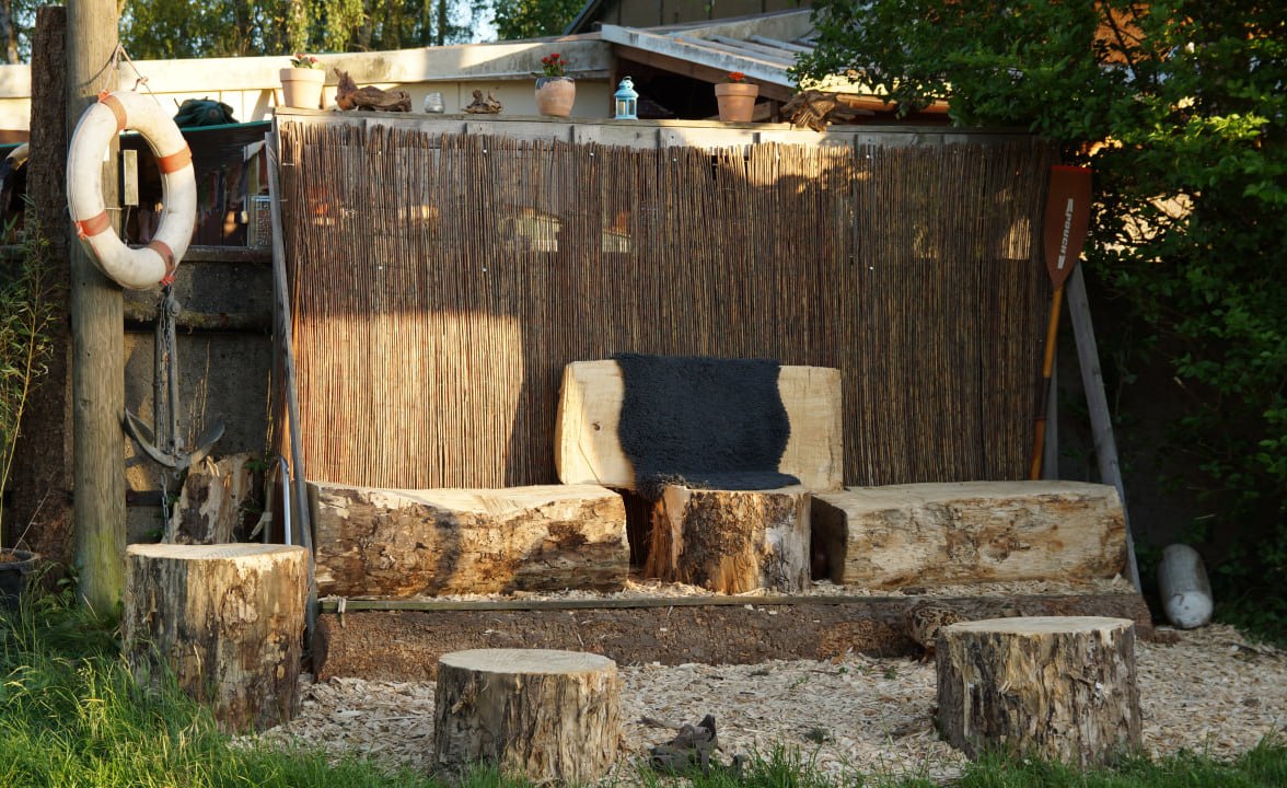 Gemütliche Sitzecke aus Baumstämmen mit Fell am Wasser